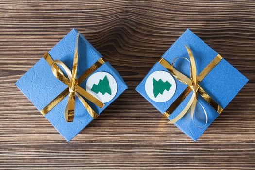 Blue gift boxes with golden ribbons on a brown wooden background for Christmas and New Year