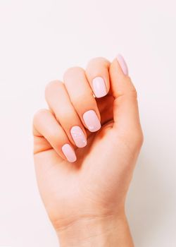 Hand of young woman with pink manicure color with art design.