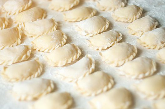 Dumplings (vareniki) with potatoes on white background - traditional Ukrainian food. Cooking raw dumplings with potatoes.