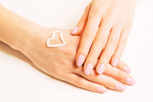 Moisturizing cream in shape of heart on a female hand, concept of skincare and beauty.