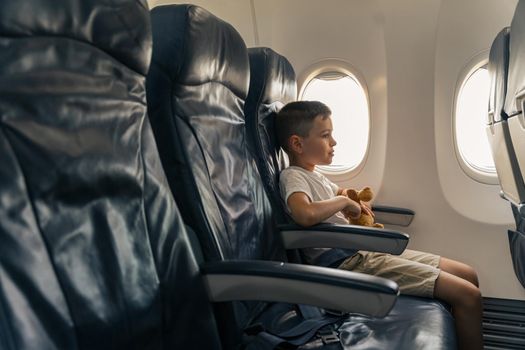 Side view of kid in air plane sitting in window seat. Traveling with children. Copy space