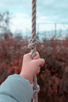 Woman hand holding the rope. Girl hand clinging to the rope, closeup.