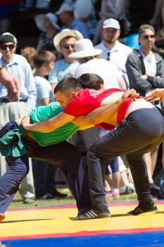 KAZAN, RUSSIA - JUNE 23, 2018: Traditional Tatar festival Sabantuy - Two young men fighting in folk wrestling kuresh outdoors, close up