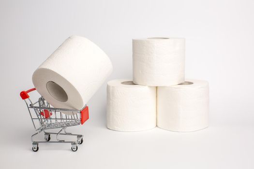 Roll of toilet paper in a toy trolley on a white background. Close-up. Panic purchase of toilet paper during quarantine. Stockpiling concept due to coronavirus outbreak