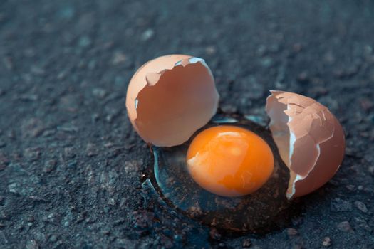 Broken egg on asphalt as a symbol of failure, negative experience, destruction, death