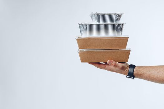 Courier hands giving packed food delivery close up against grey background