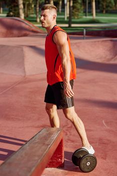 male athlete with dumbbells in hands training in the park. High quality photo