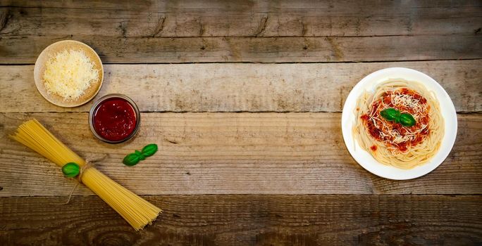 Spaghetti Pasta with Tomato Sauce, Cheese and Basil on Wooden Table. Traditional Italian Food. Banner. Top View Flat Lay. Copy Space For Your Text.