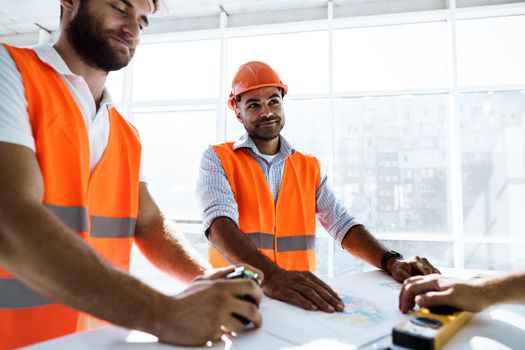 Two young engineers man looking at project plan on the table in construction site