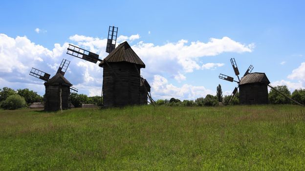 Ukraine, Kiev - June 11, 2020. Old Ukrainian wooden windmills of the XIX century. Summer outdoor landscape. Open-air museum of folk architecture and life, Pirogovo, Ukraine. Tourism and travel
