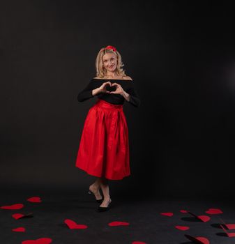 Girl stands around cardboard hearts happy valentine background,, on the floor hearts romance . February 14 . love festive, hearts in red dress girl, barefoot