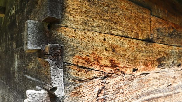 Wall, facade, corner of a wooden planed pine log house in the village. A brown rustic wood texture background. Architecture. Green building.