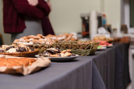 A lot of cookies lie on the grey table. blurred background. holiday or party concept. girl in the background.