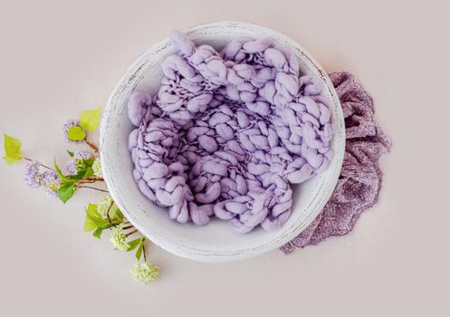 Beautiful backdrop for newborn photosession with flowers hydrangea. Digital composite with basin filled with knitted blanket isolated on light pink background