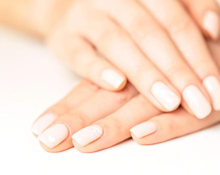 Female hands with smooth skin and stylish beige pastel manicure.