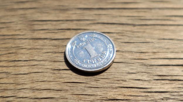 One new 2018 hryvnia coin on a wooden background. Ukrainian money.