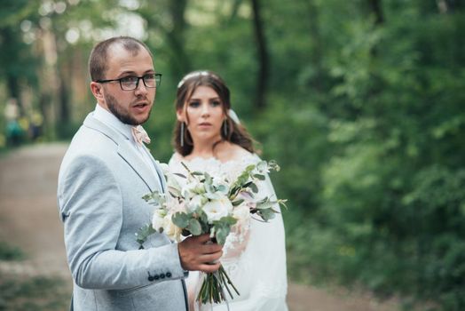 Wedding photo of the bride and groom in a gray-pink color on nature in the forest and rocks