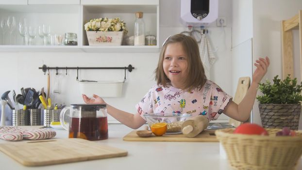 Little girl laughing on the kitchen with brewing teapot, close up