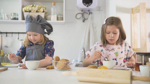 Two cute little girls decorating cookies with jam, close up