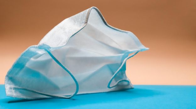 One 3-layer disposable surgical face mask with rubber pads to cover the mouth and nose. The concept of protection from bacteria, healthcare and medicine. COVID-19. Dangerous virus.