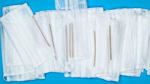 Coronavirus protection. Antiviral protective medical face masks with ear loops. Surgical mask background. Respiratory syndrome, coronavirus disease COVID-19. Many folded medical masks