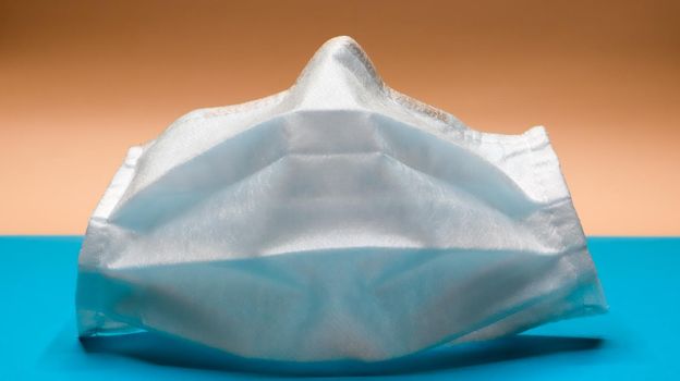 One 3-layer disposable surgical face mask with rubber pads to cover the mouth and nose. The concept of protection from bacteria, healthcare and medicine. COVID-19. Dangerous virus.