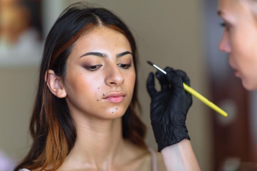 Makeup woman artist at work, professional in action with young model in beauty salon and creative classes