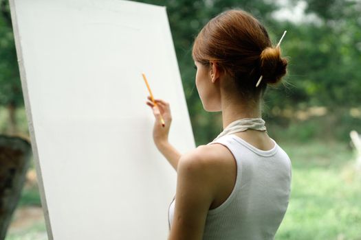 an artist in nature draws on an easel with a pencil. High quality photo