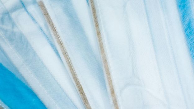 Coronavirus protection. Many antiviral protective medical face masks with ear loops spread out on a blue background. Surgical mask background. Respiratory syndrome, coronavirus disease COVID-19