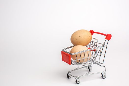 Beige chicken eggs in the shopping cart. White isolated background. Healthy food concept.