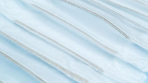 Coronavirus protection. Many antiviral protective medical face masks with ear loops spread out on a blue background. Surgical mask background. Respiratory syndrome, coronavirus disease COVID-19