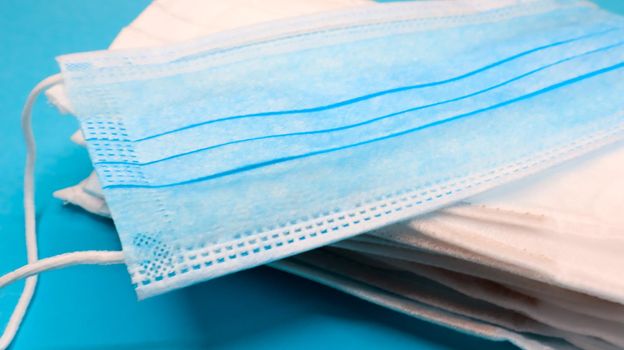 Coronavirus protection. Antiviral protective medical face masks with ear loops. Surgical mask background. Respiratory syndrome, coronavirus disease COVID-19. Many folded medical masks