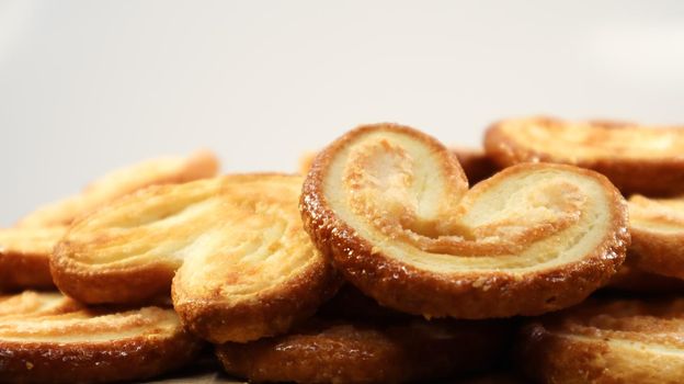 Fresh puff pastry palm cookies in the shape of a heart. Classic French pastries. Pig ear, elephant ear cookies, French hearts