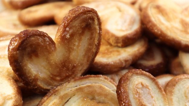 Fresh puff pastry palm cookies in the shape of a heart. Classic French pastries. Pig ear, elephant ear cookies, French hearts