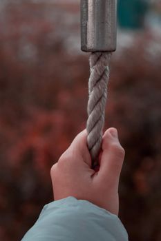 Woman hand holding the rope. Girl hand clinging to the rope, closeup.