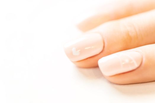 Female fingers with professional manicure and natural beige color polish, close-up.