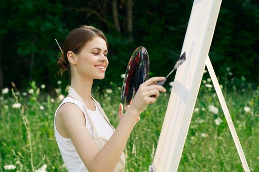 cheerful woman paints a picture palette nature landscape. High quality photo