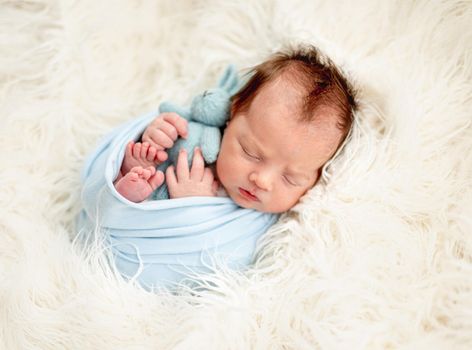 Cute newborn sleeping with toy in tiny hands