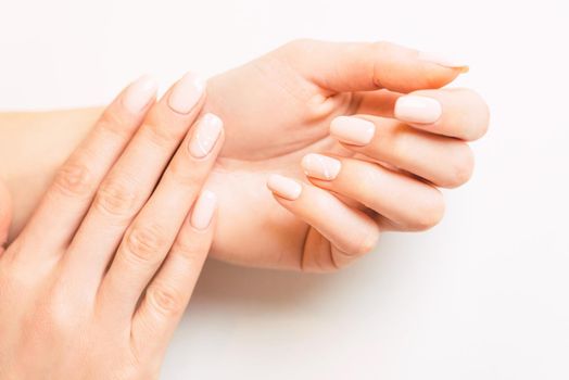 Beautiful young female hands with stylish professional manicure, nails of pastel natural color. Concept of beauty salon.