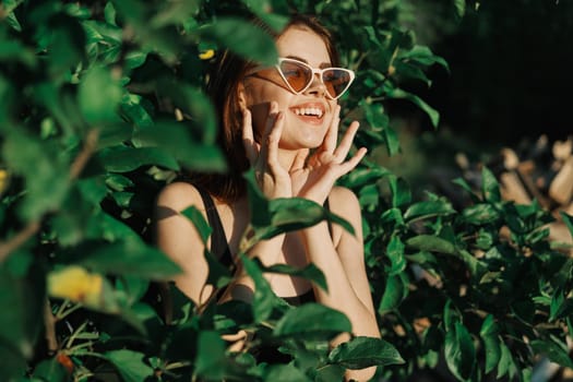 smiling woman wearing sunglasses green leaves nature fashion. High quality photo