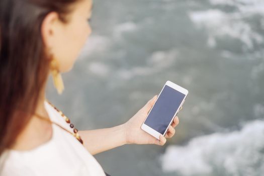 Young woman using smartphone while walking near the river, mock-up.