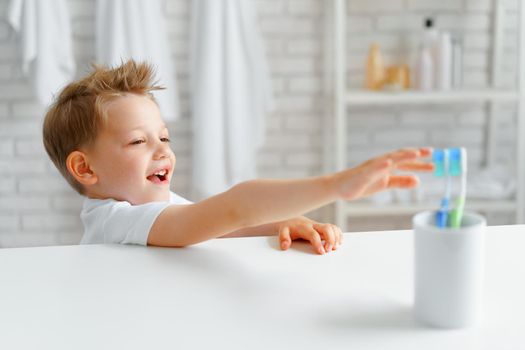 Cute Little boy reaching out for toothbrush in bathroom