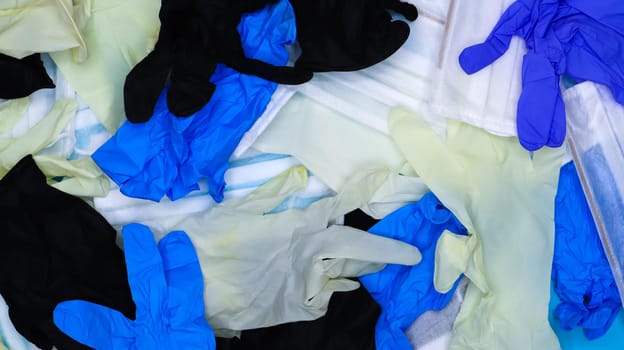 Multicolored crumpled latex surgical gloves and medical protective masks lie in disarray. Flat lay. Used remedies against the Covid-19 virus.