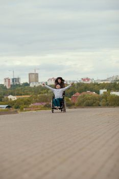 Young woman with happy disabled man in wheelchair having fun outdoors, close up
