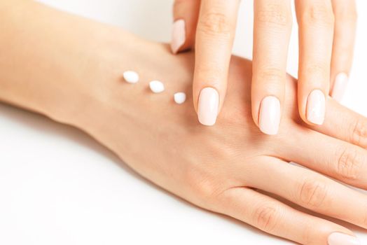 Young female hands applying moisturizing cream for smooth skin, concept of skincare and beauty.