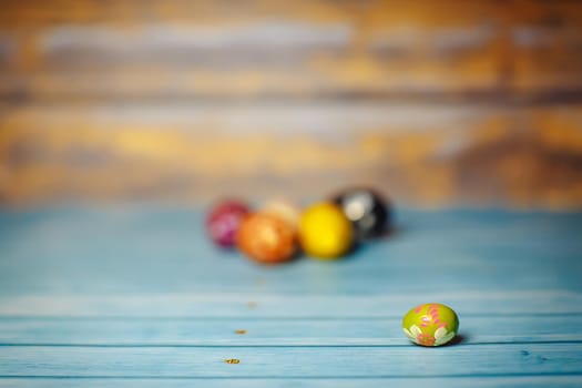 Easter colored painted small egg on blue and brown blurry wooden background with copyspace