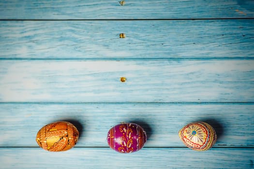 Easter colored painted eggs on blue wooden background flat lay with copy space
