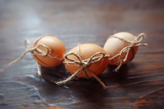 Easter beige eggs decorate with rope on brown wooden background with copyspace