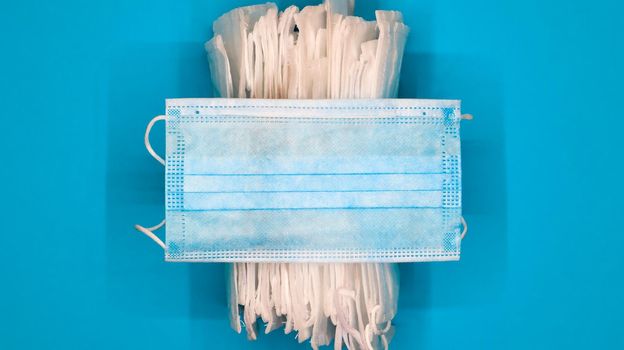 Coronavirus protection. Antiviral protective medical face masks with ear loops. Surgical mask background. Respiratory syndrome, coronavirus disease COVID-19. Many folded medical masks