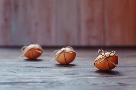 Easter beige eggs decorate with rope on brown wooden background with copyspace